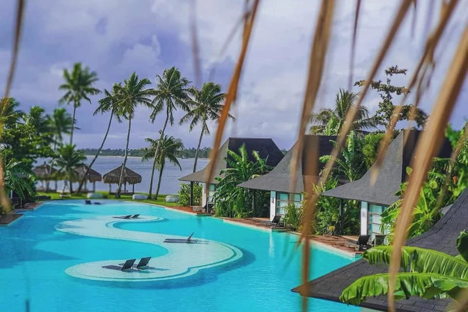 The resort pool and floating villas framed by palms
