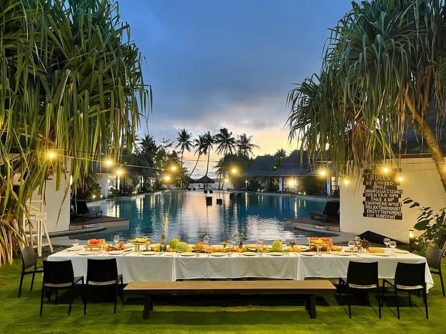 Poolside dining table set with fresh dishes at sunset