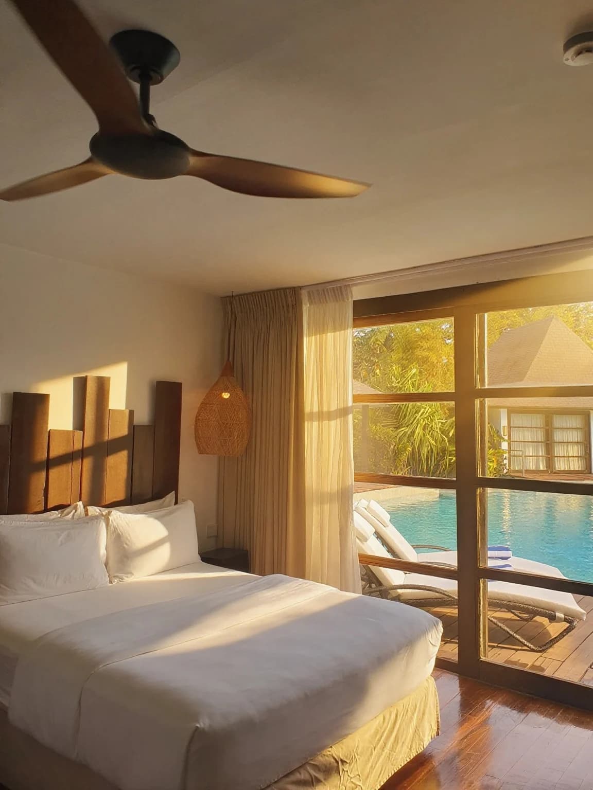 Sunlit lagoon villa bedroom overlooking the resort pool